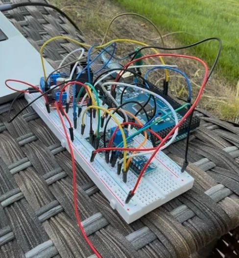 The instrument on a breadboard beside four steel electrodes driven into soil, with the serial output showing apparent resistivity.